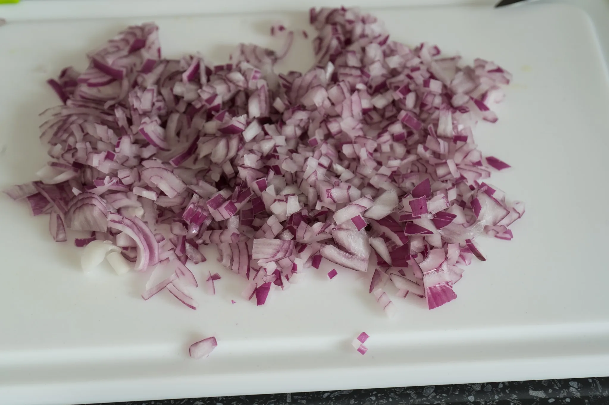 Grated zucchini being added to Arborio rice and red onion in a wide pan