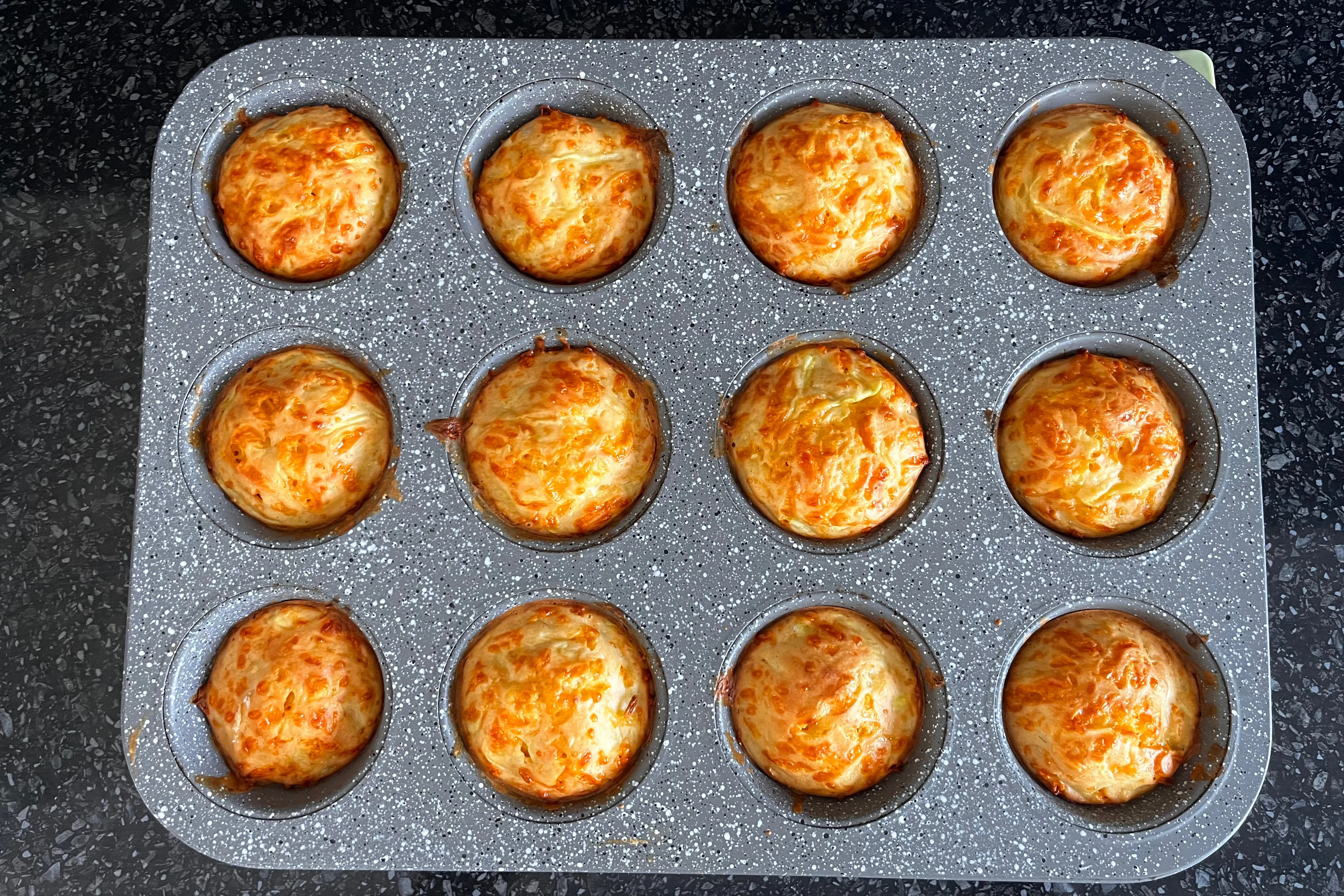 Golden zucchini and Cheddar muffins baked in a 12-hole muffin tin