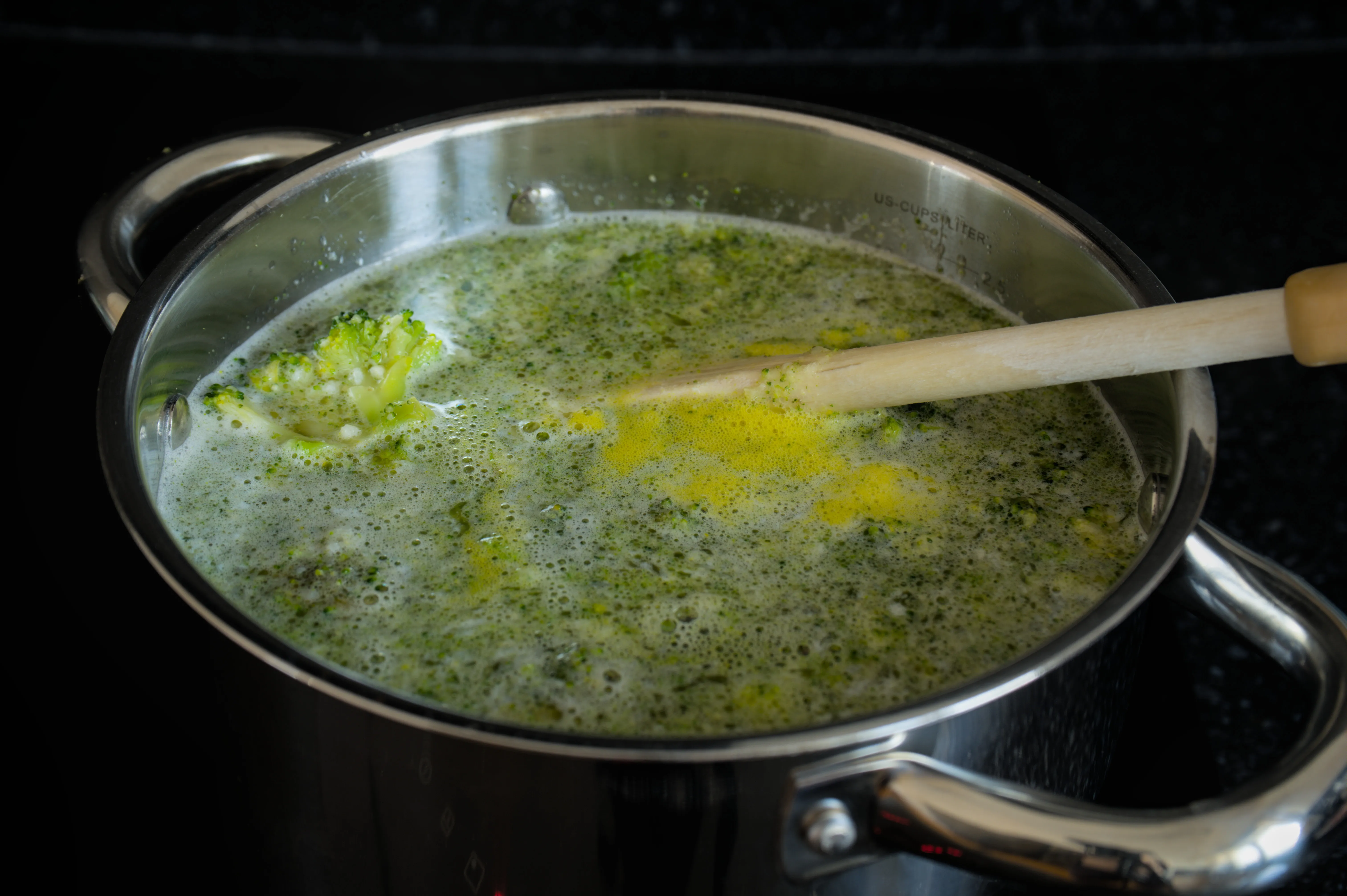 Broccoli soup with visible florets simmering in a stainless-steel pot before blending