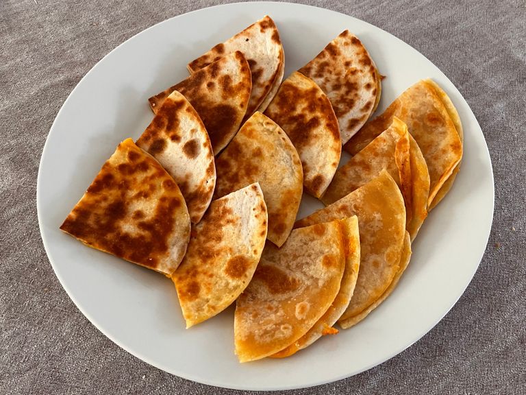Golden cheese quesadilla wedges on a white plate