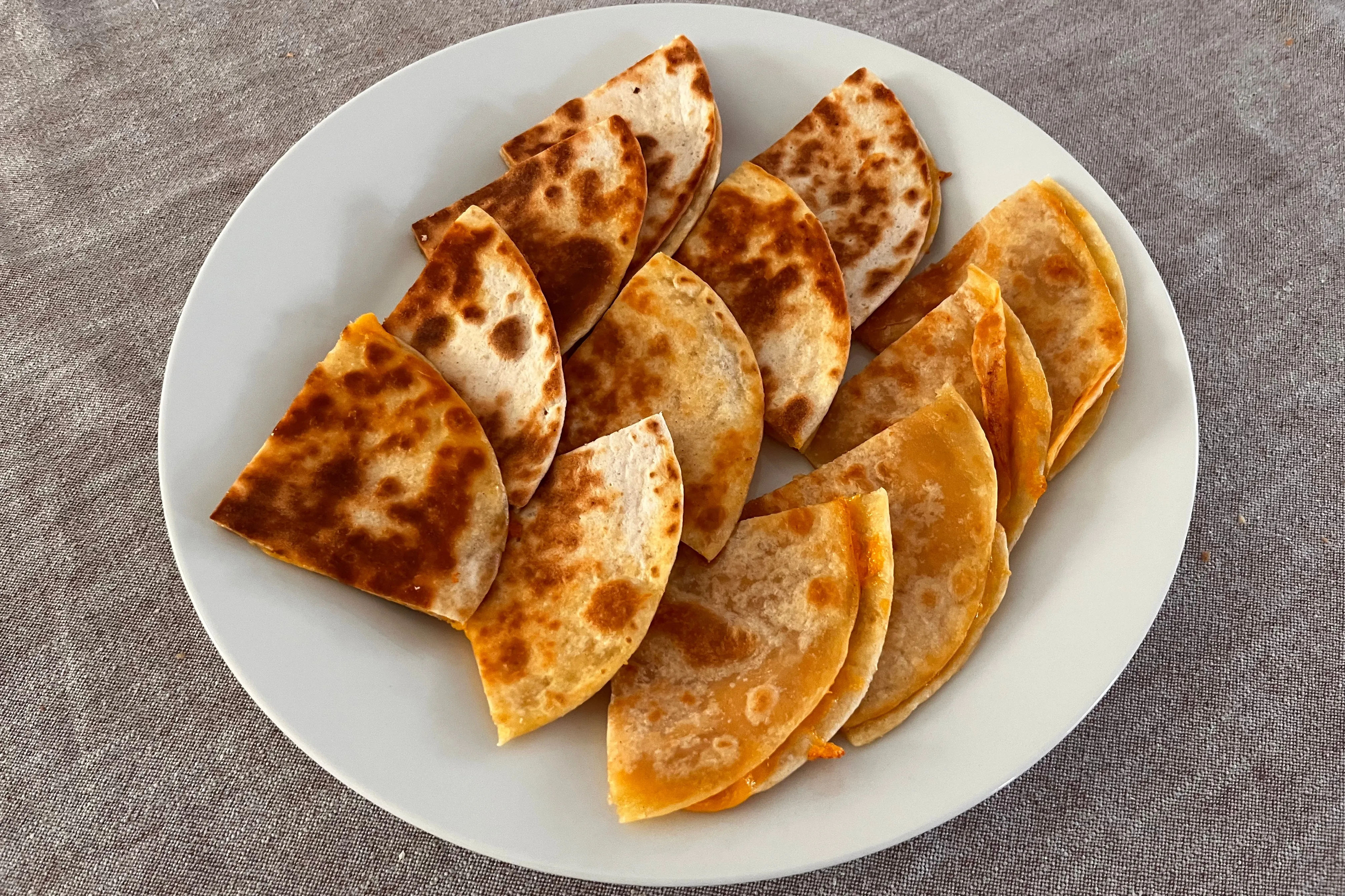 Golden cheese quesadilla wedges on a white plate