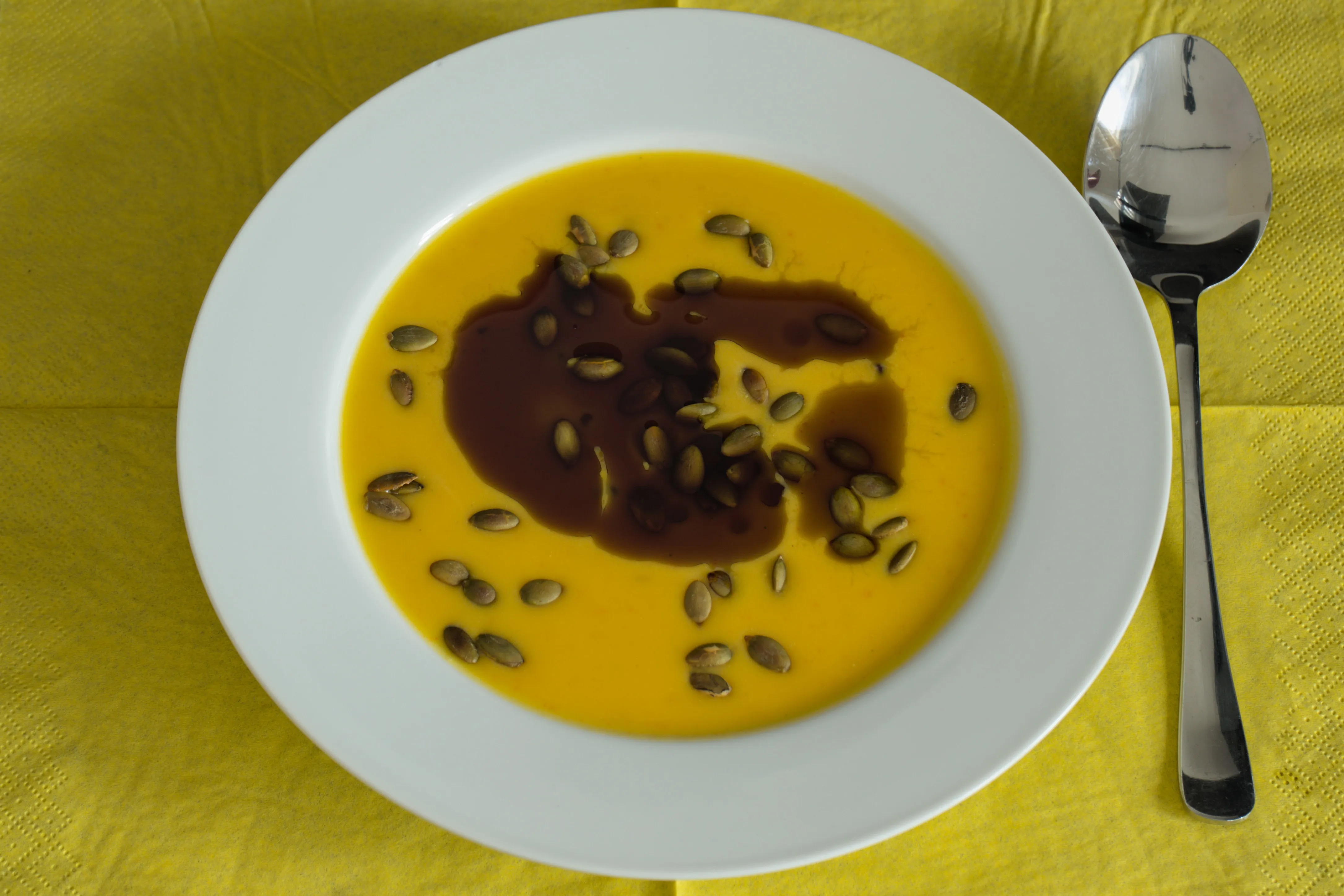 Creamy Hokkaido pumpkin soup with pumpkin seeds and pumpkin seed oil in a white bowl