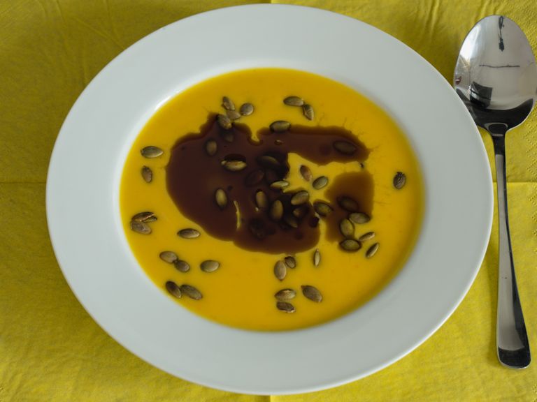 Creamy Hokkaido pumpkin soup with pumpkin seeds and pumpkin seed oil in a white bowl