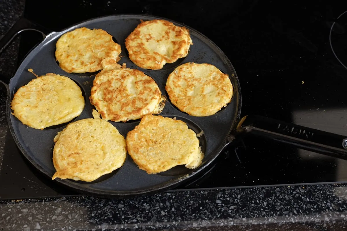 Potato and zucchini fritters browned after being turned in a pancake-well pan