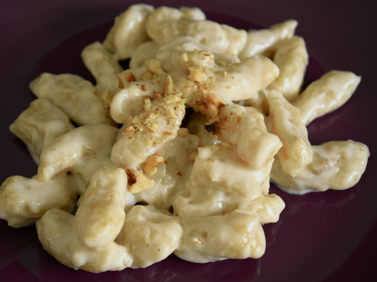 Homemade potato gnocchi in creamy Grana Padano sauce topped with toasted walnuts
