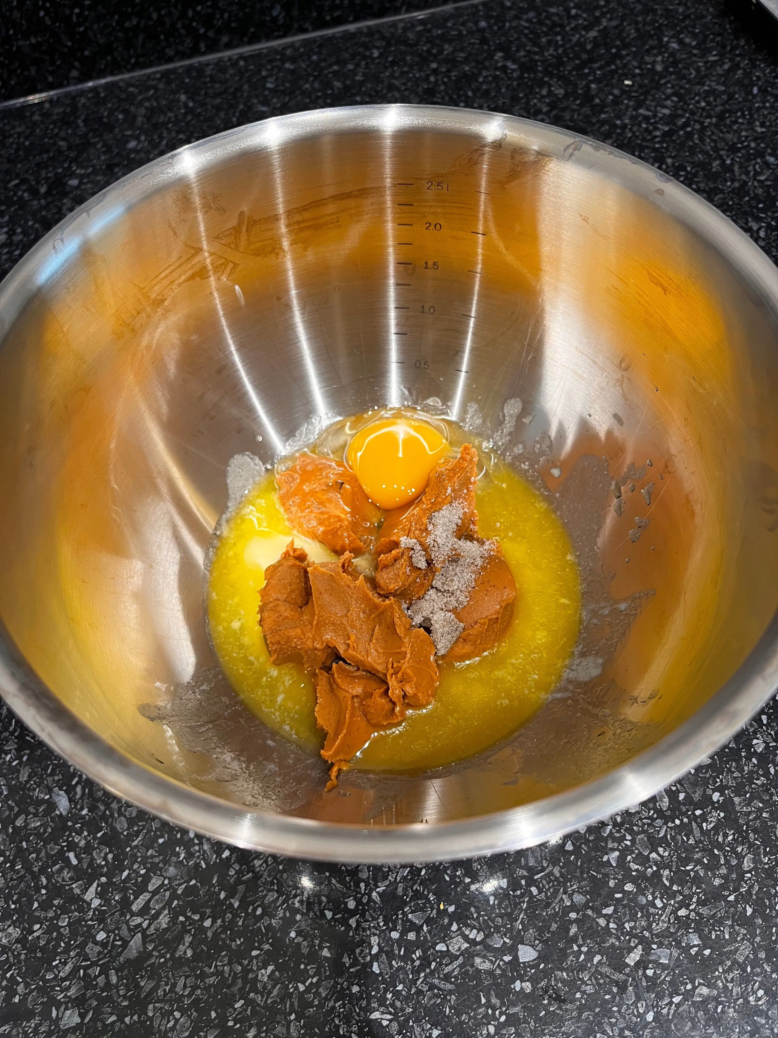 Melted butter, smooth peanut paste and an egg in a mixing bowl before mixing