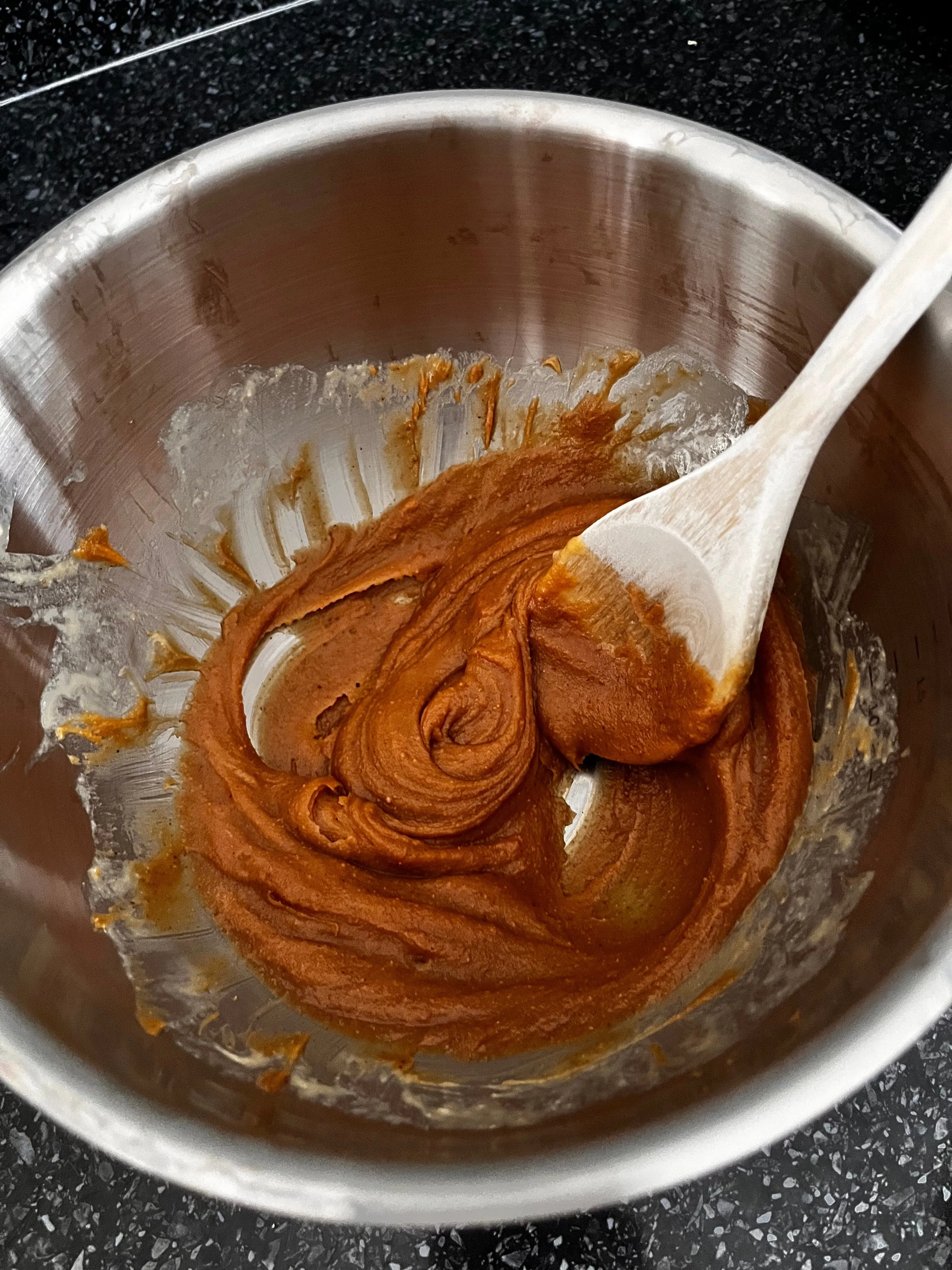 Smooth peanut butter cookie wet mixture in a bowl with a wooden spoon