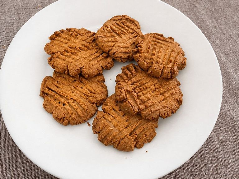 Peanut butter cookies with fork crosshatches piled on a white plate