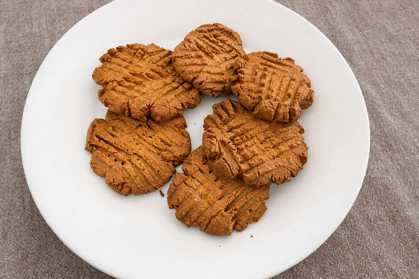 Peanut butter cookies with fork crosshatches piled on a white plate