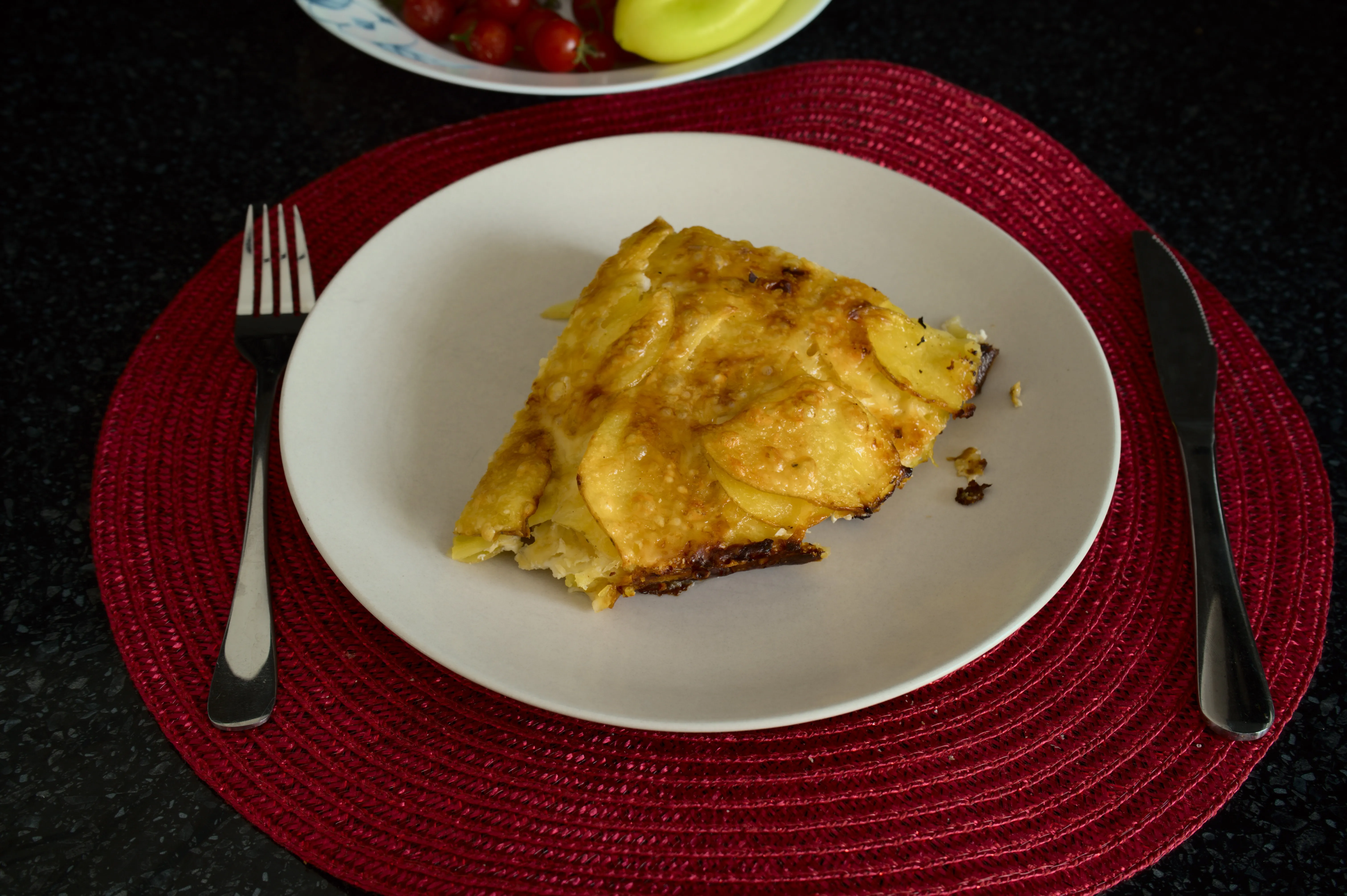 A serving of golden potato and zucchini gratin with Gouda and Parmesan on a white plate