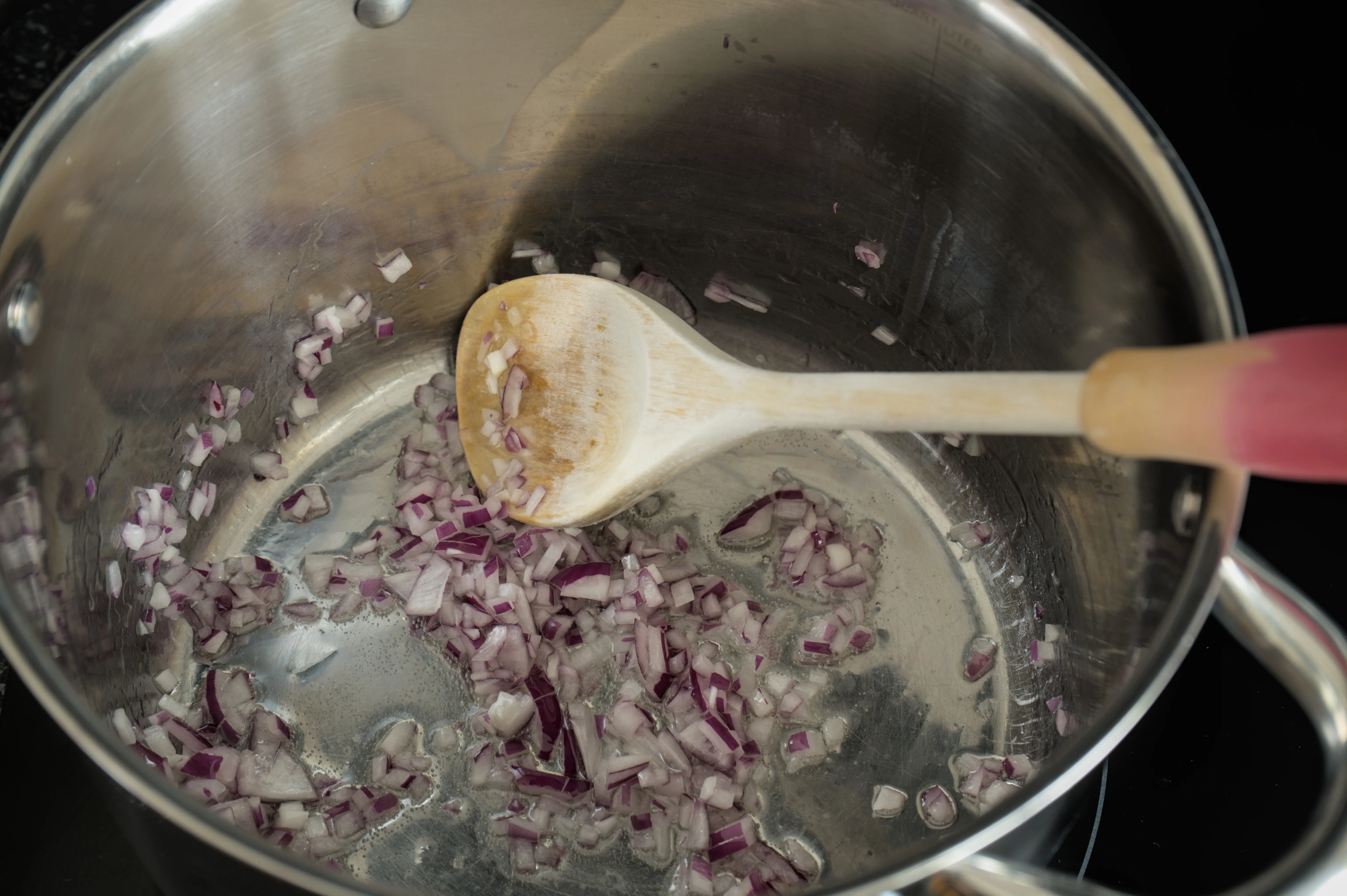 Finely chopped red onion softening in olive oil in a pot
