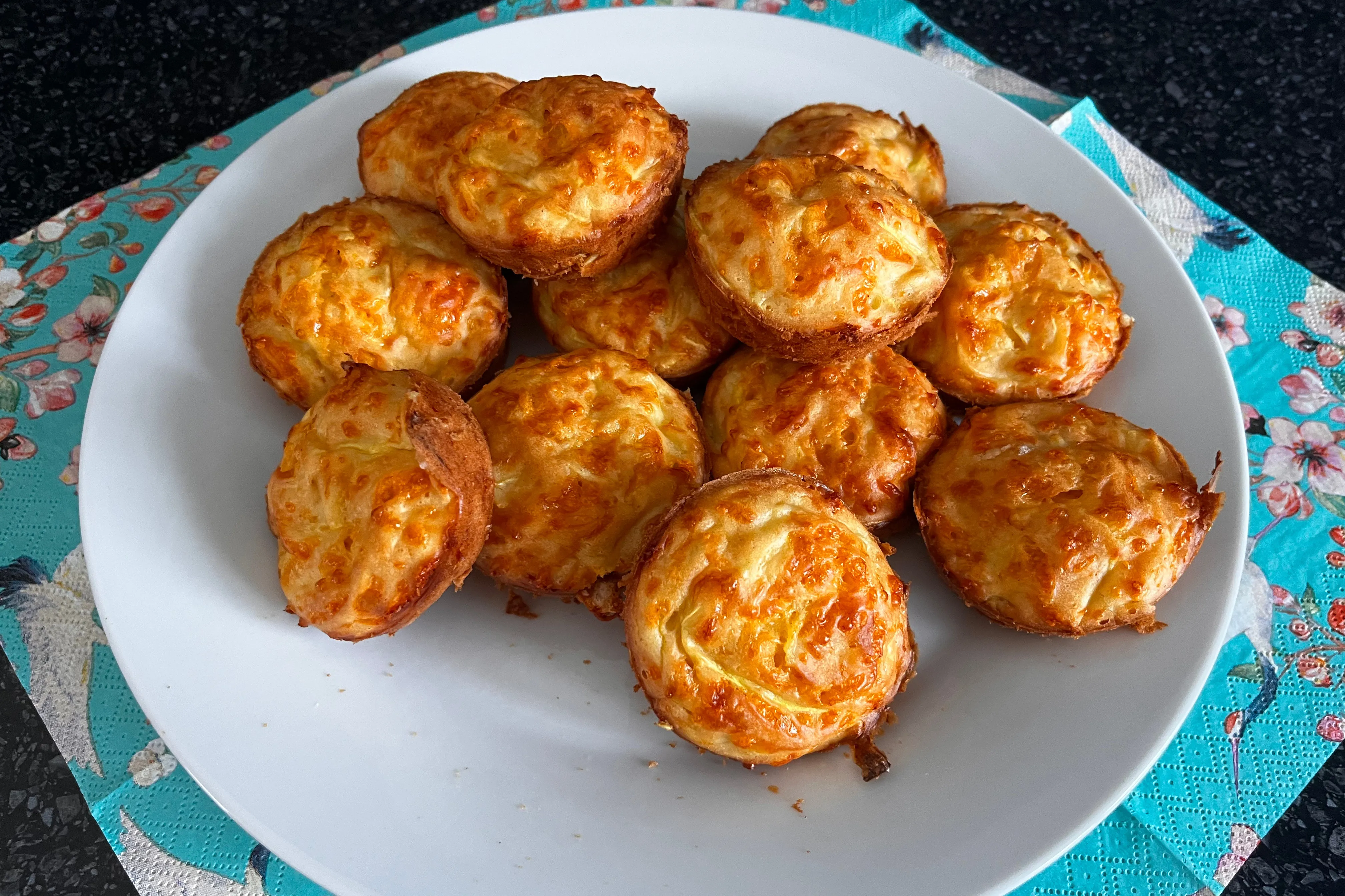 Golden savory zucchini and Cheddar muffins piled on a white plate