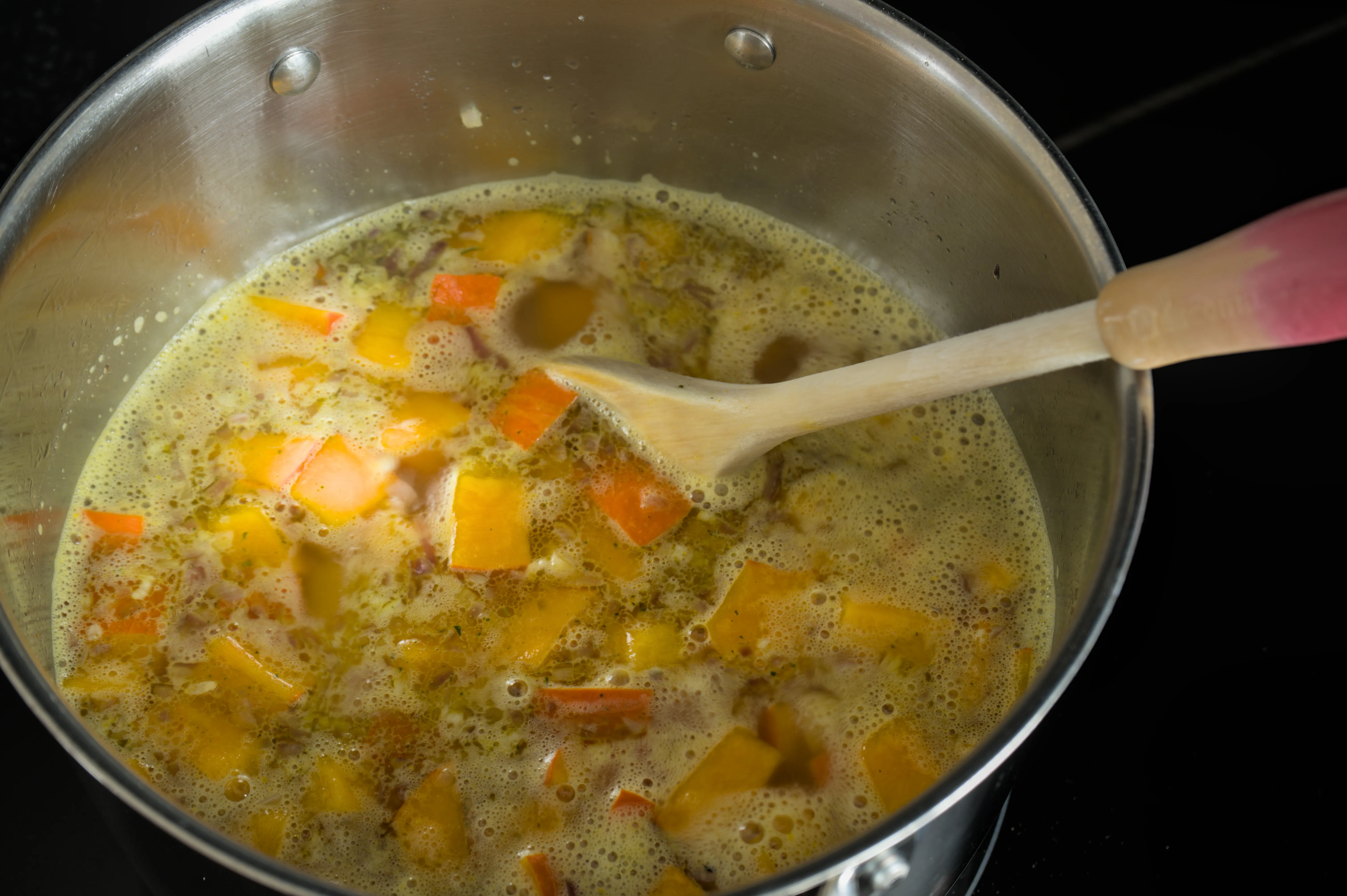 Hokkaido pumpkin and potato simmering in chicken stock in a pot