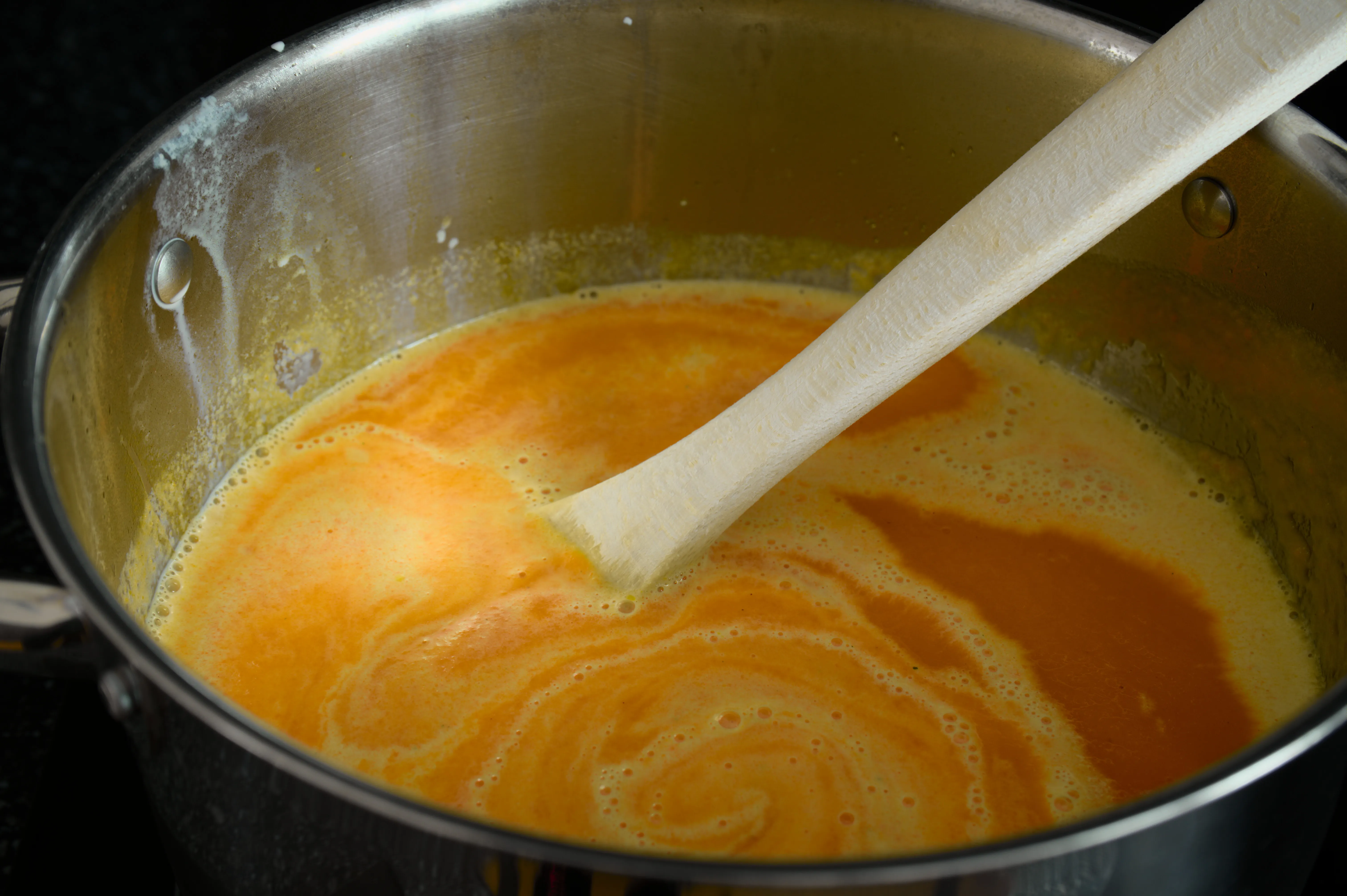 Kochsahne wird in fein pürierte Karottensuppe im Topf eingerührt