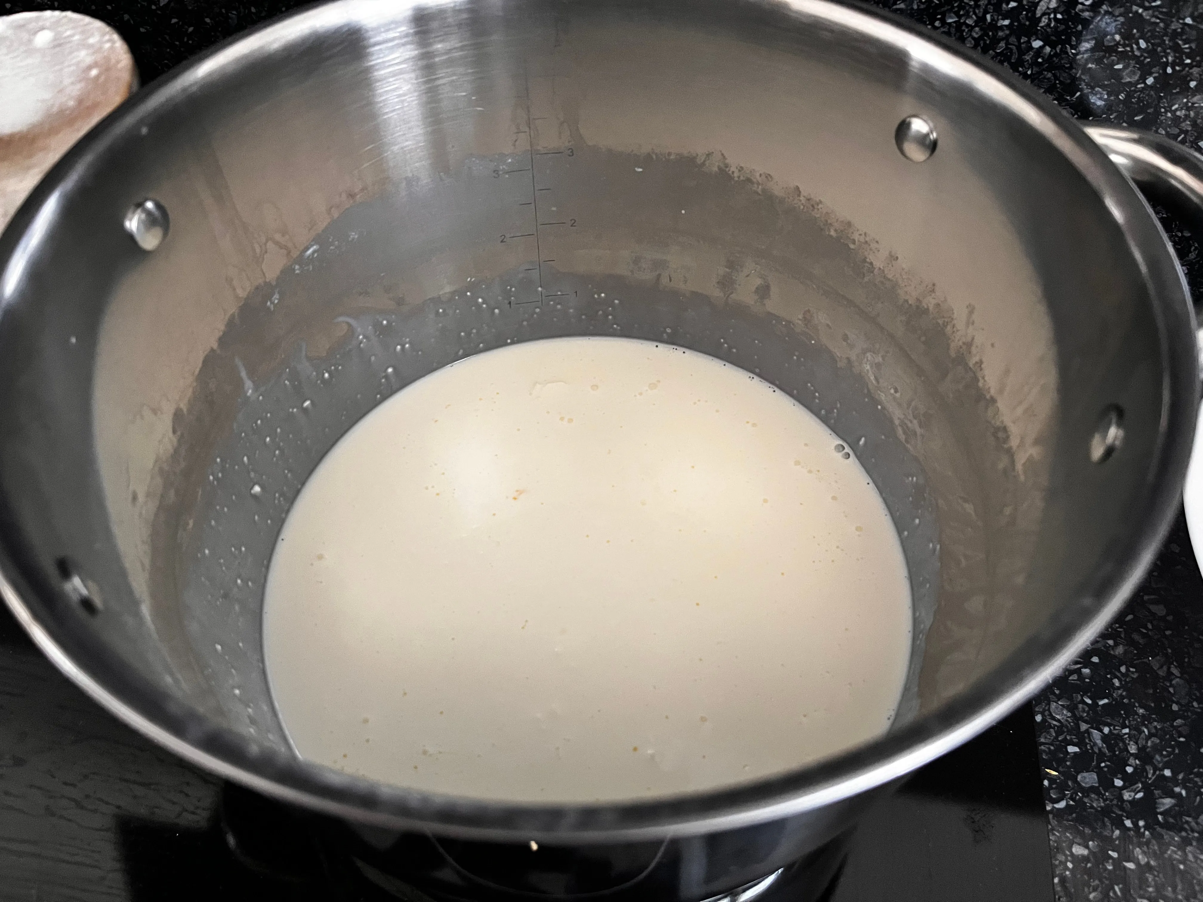 Whipping cream heating in a saucepan for three-cheese macaroni