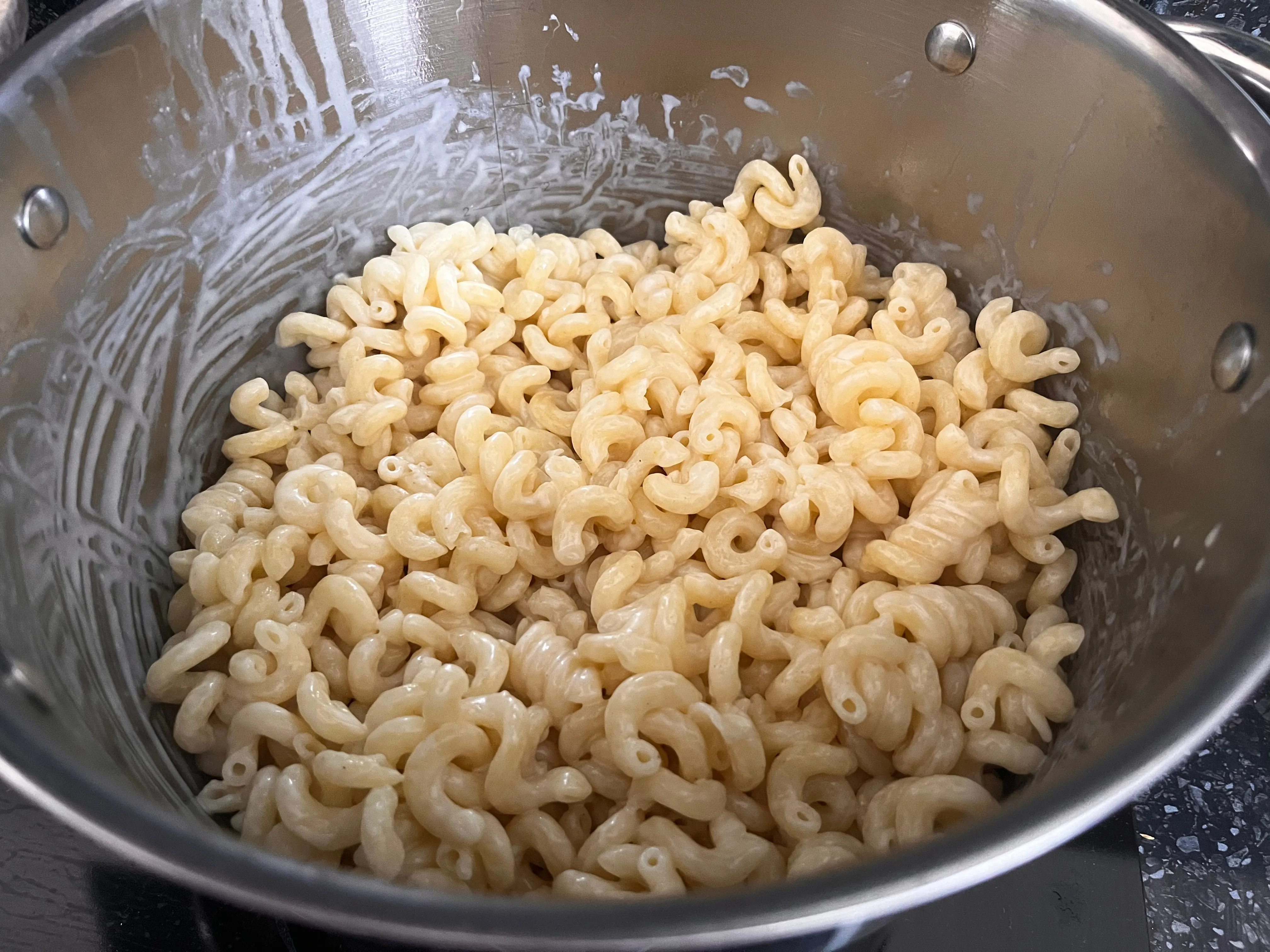 Macaroni mixed with melted cheese sauce in a pot
