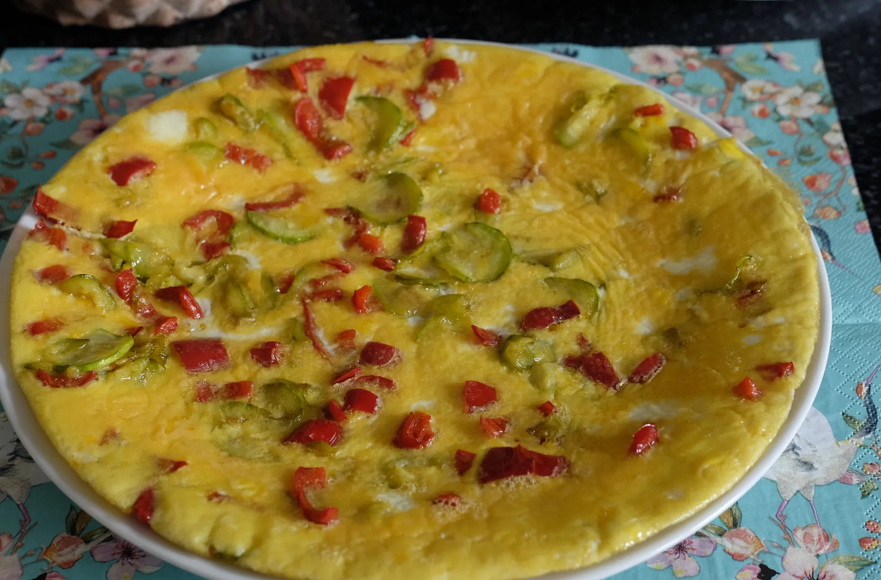 Finished thin zucchini omelette with pieces of red bell pepper